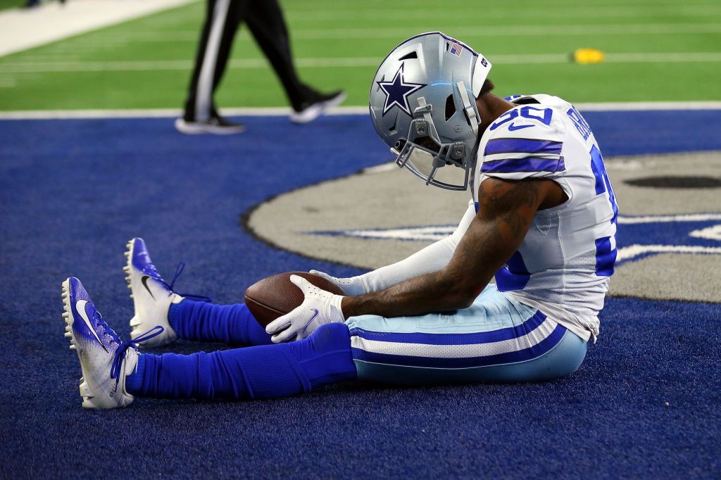 A Dallas Cowboys player sitting in the end zone with a dejected expression after a loss.